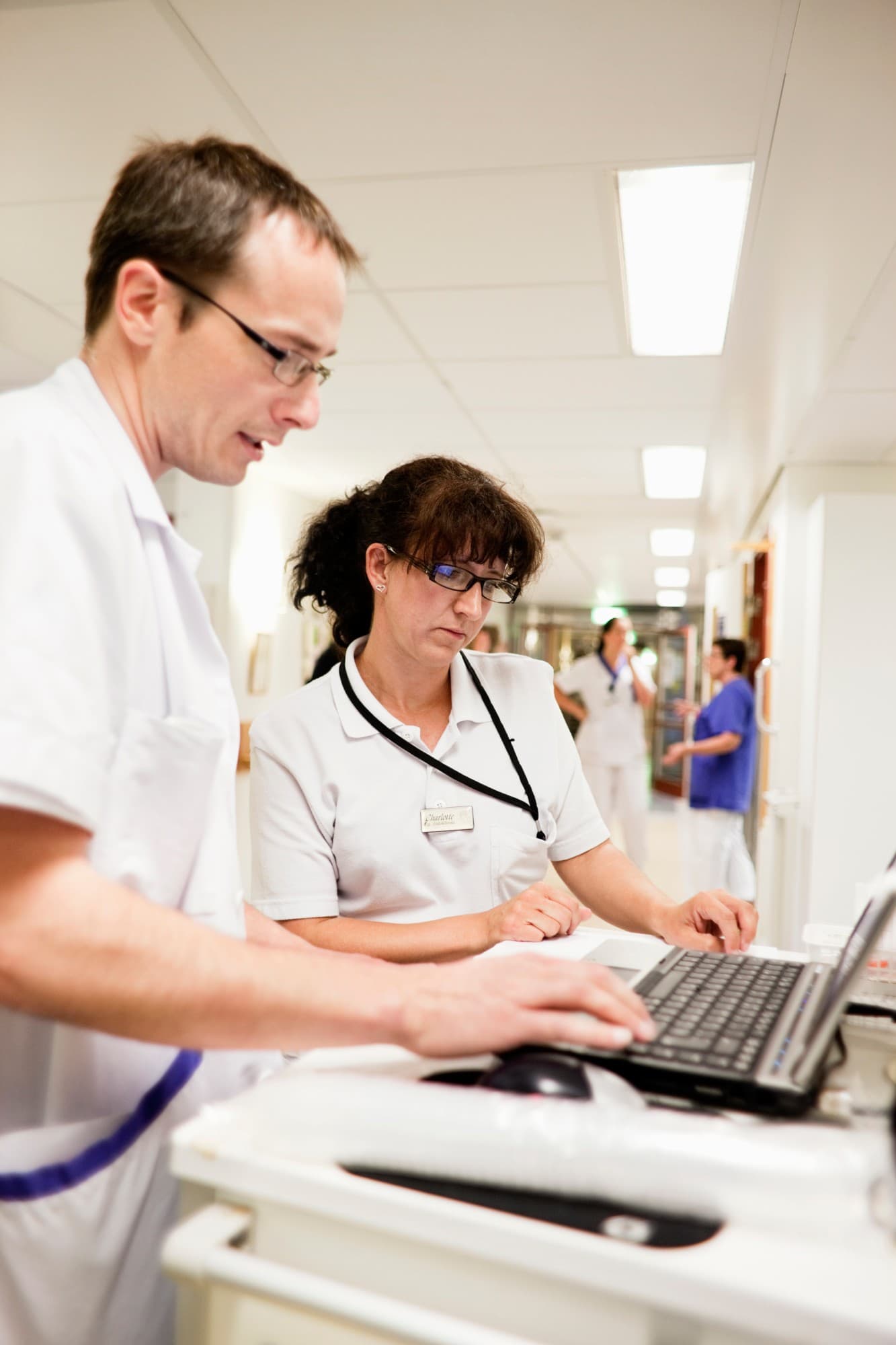 Cadre de santé et infirmière consultant un ordinateur dans un couloir de service hospitalier
